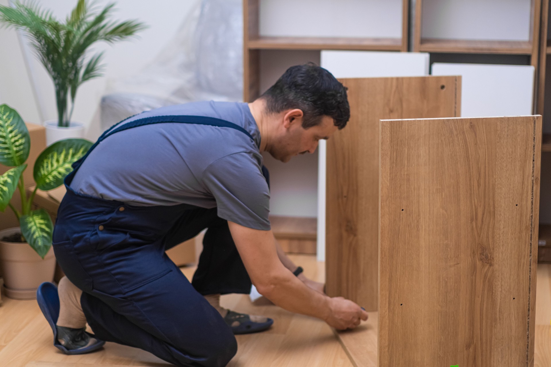 Furniture fixing and delivery company worker assembling wooden cabinet