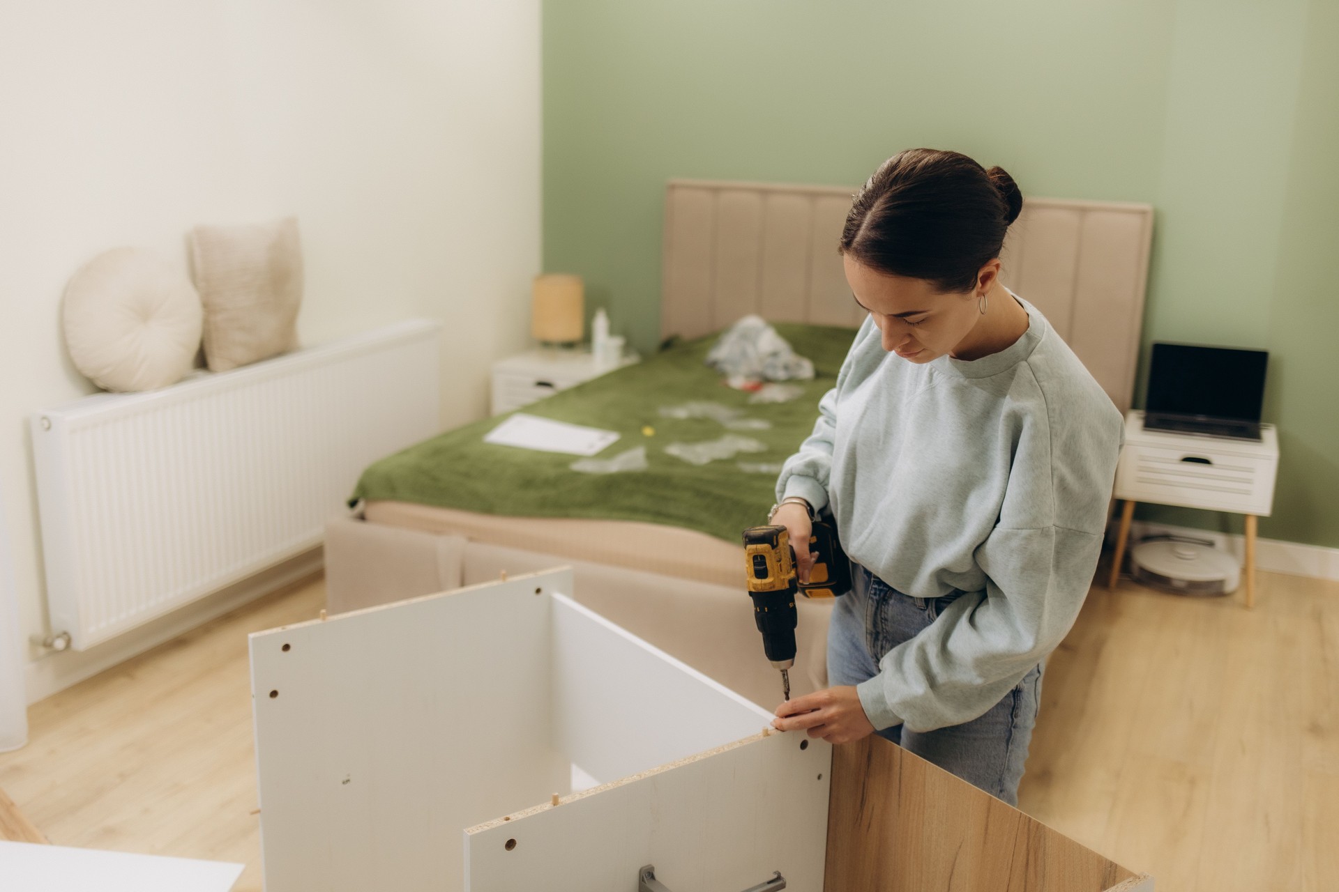 Woman assembling furniture at home with cordless screwdriver