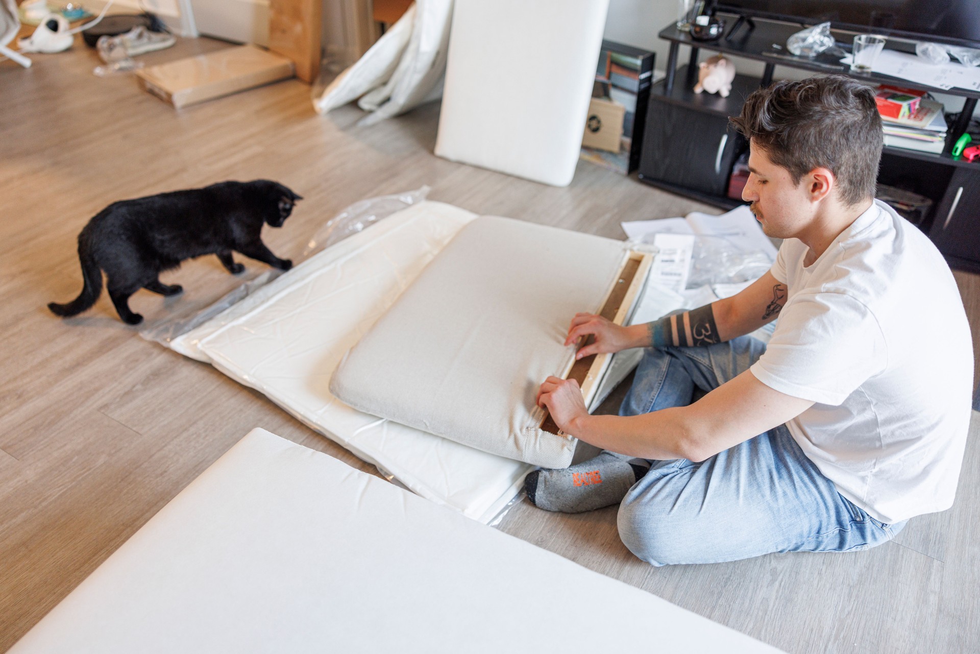 Navy soldier and black cat: they assemble a sofa on the floor of a bright living room